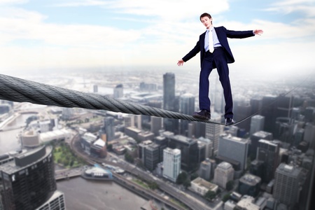 Business man balancing on the rope high in the skyの写真素材