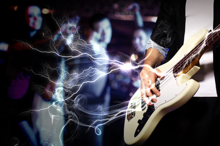 Young guitar player with instrument performing in night club
