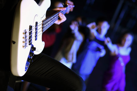 Young guitar player with instrument performing in night club