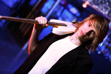 Young guitar player with instrument performing in night club