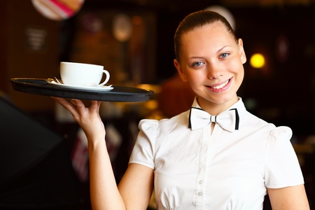 Portrait of young waitress in white blouse holding a trayの写真素材