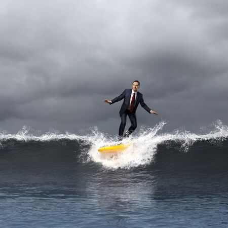 Image of young business person surfing on the waves of the oceanの写真素材