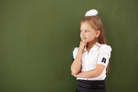 Scoolgirl standing in class near a green blackboardの写真素材