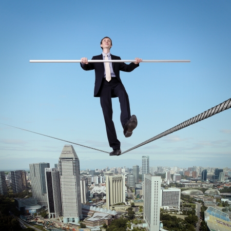 Business man balancing high over a cityscape の写真素材