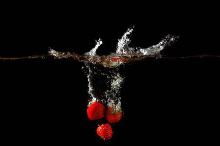 Colored red paprika in water splashes on black backgroundの写真素材