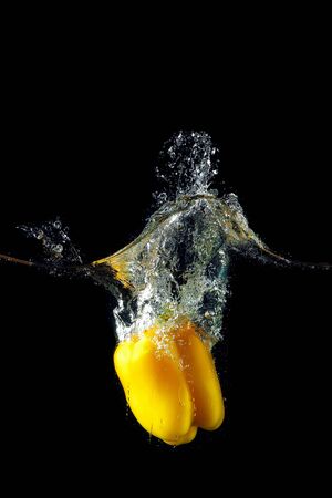 Colored yellow paprika in water splashes on black backgroundの写真素材