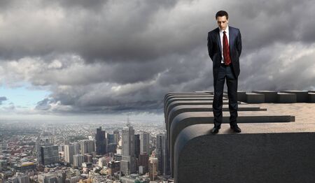Business man standing high over a cityscapeの写真素材