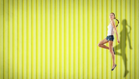 pretty modern slim hip-hop style woman jumping dancing on a colour backgroundの写真素材