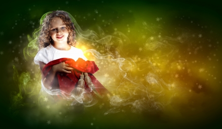 A cute young girl holding a christmas gift, dark background with christmas light bokehの写真素材