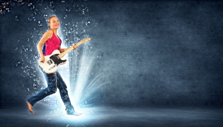 young woman playing on electro guitar and jumpingの写真素材