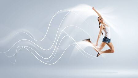 Modern style female dancer jumping and posing with lightingの写真素材