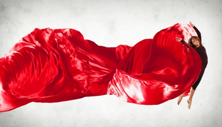 Portrait of a dancing young woman with red fabricの写真素材