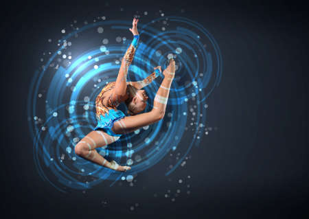 Young cute woman in gymnast suit show athletic skill on black backgroundの写真素材