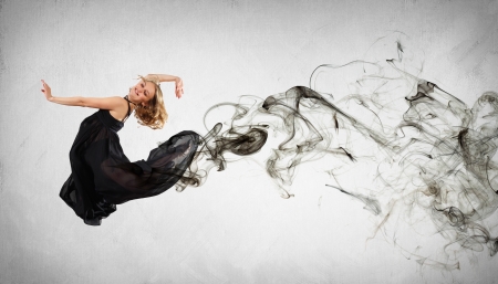 Beautiful young dancer with black smoke curles around herの写真素材