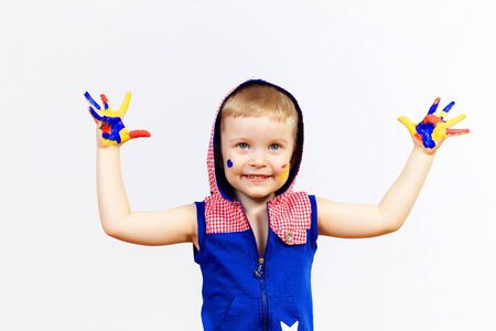 little child with hands painted in colorful paints ready for hand printsの写真素材