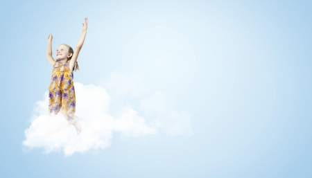 Photo of little girl jumping and raising hands against light backgroundの写真素材