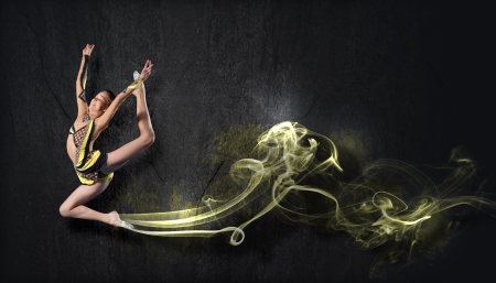 Young cute woman in gymnast suit show athletic skill on black backgroundの写真素材