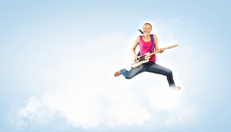 young woman playing on electro guitar and jumpingの写真素材