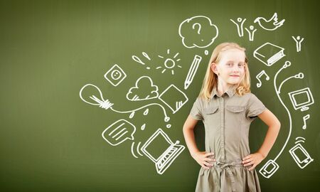 Scoolgirl standing in class near a green blackboardの写真素材