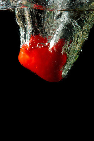 Colored red paprika in water splashes on black backgroundの写真素材
