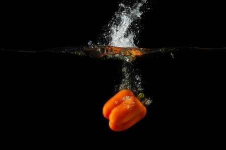 Colored orange paprika in water splashes on black backgroundの写真素材