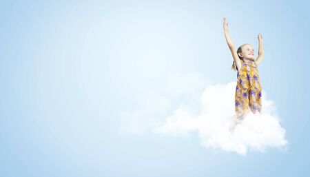 Photo of little girl jumping and raising hands against light backgroundの写真素材