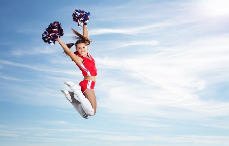 Young beautiful female cheerleader in uniform jumping highの写真素材