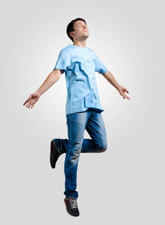 Modern slim hip-hop style man jumping dancing on a grey backgroundの写真素材