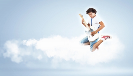 young man playing on electro guitar and jumpingの写真素材