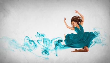 Portrait of a dancing young woman with blue smoke curlesの写真素材