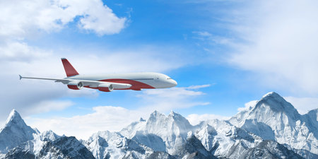 White passenger plane flying in the blue sky above the mountains with snow tops