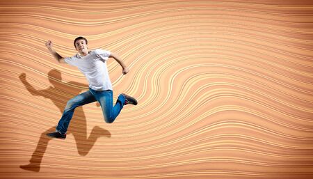 pretty modern slim hip-hop style man jumping dancing on a colour backgroundの写真素材