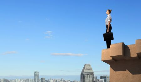 Business woman standing high over a cityscapeの写真素材