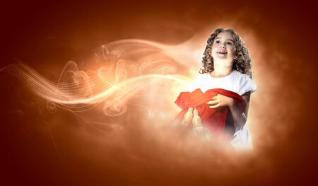 A cute young girl holding a christmas gift, dark background with christmas light bokehの写真素材