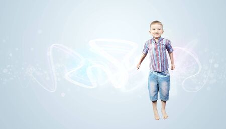 Photo of little boy jumping and raising handsの写真素材