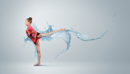 Young cute woman in gymnast suit show athletic skill on white backgroundの写真素材