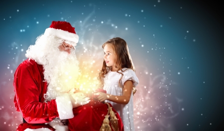 Portrait of Santa Claus with a little girl looking at a giftの写真素材