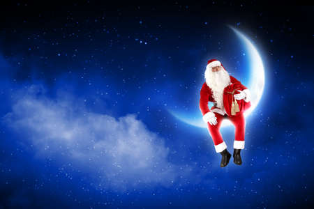 a Santa Claus sitting on shiny moon above winter forestの写真素材