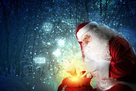 Santa with beard and red hat holding and looking into the sackの写真素材