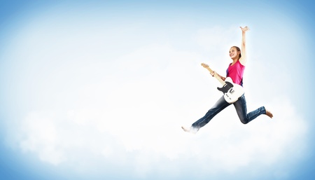 young woman playing on electro guitar and jumpingの写真素材