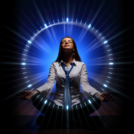 Young businesswoman sitting against blue background with clock interfaceの写真素材