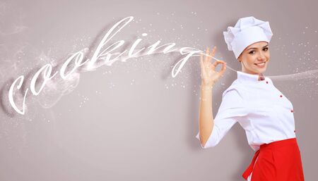 Young female chef in red apron against collour backgroundの写真素材