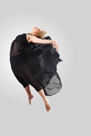 Young female dancer jumping against white backgroundの写真素材