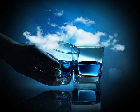 Two glasses of blue liquid against cloudy backgroundの写真素材