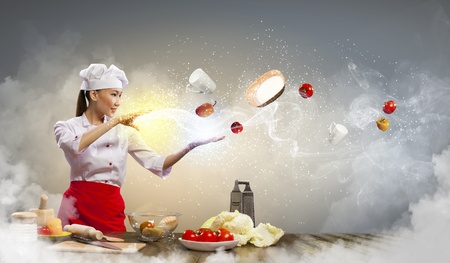 Asian female cooking with magic against color backgroundの写真素材