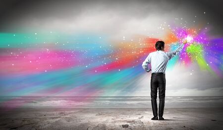 young man standing with back painting splashes with fingersの写真素材