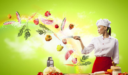 Asian female cook with knife cutting fruits and vegetables in airの写真素材