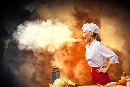 Asian female cook in anger against color background with shine effectsの写真素材