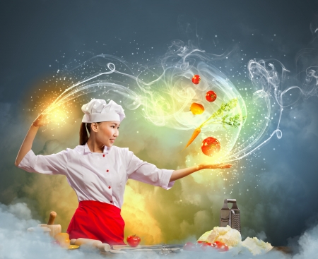 Asian female cooking with magic against color backgroundの写真素材