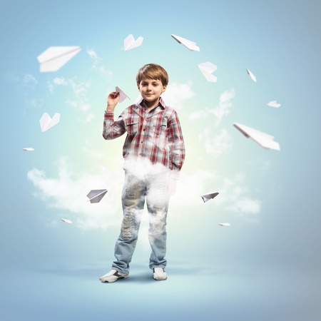 Image of little boy playing with paper airplane against blue backgroundの写真素材